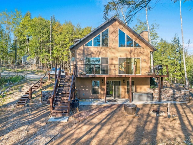 W6554 Wolf Lake Rd, Wausaukee, WI 54177 - rear view of property featuring stairway, an outdoor hot tub, a wooden deck, a patio area, and a chimney