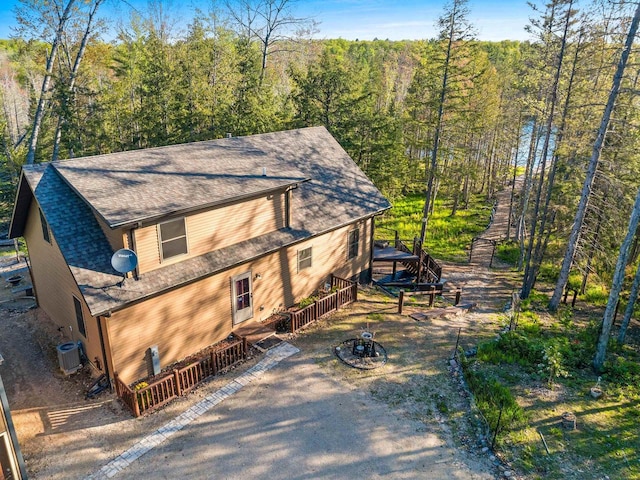 W6554 Wolf Lake Rd, Wausaukee, WI 54177 - view of front of property with a deck, central air condition unit, a shingled roof, and a forest view