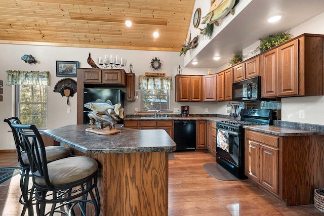 W6554 Wolf Lake Rd, Wausaukee, WI 54177 - kitchen featuring black appliances, wood ceiling, dark countertops, a breakfast bar, and a sink