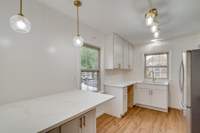 1904 75th St, Kenosha, WI 53143 - kitchen with freestanding refrigerator, a sink, light wood finished floors, pendant lighting, and light stone countertops