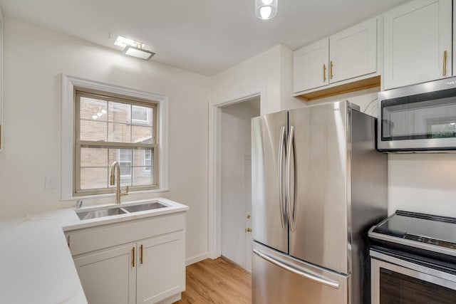1904 75th St, Kenosha, WI 53143 - kitchen featuring appliances with stainless steel finishes, a sink, light wood-style floors, white cabinetry, and light countertops