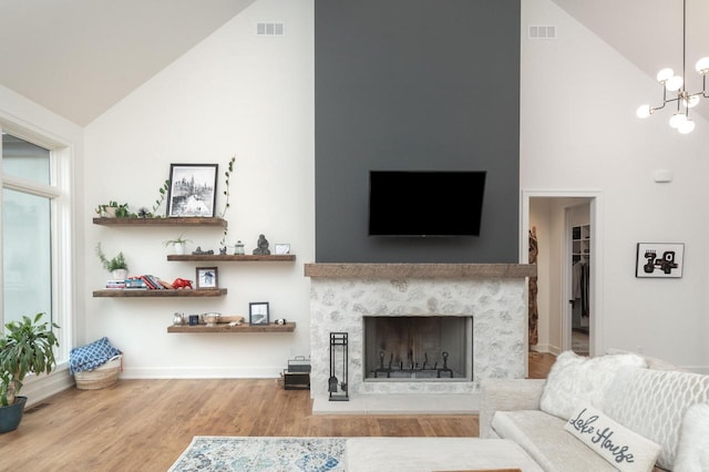 W329N6597 Forest Dr, Hartland, WI 53029 - living room with high vaulted ceiling, wood finished floors, a premium fireplace, a chandelier, and baseboards
