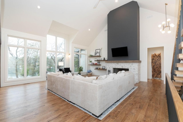 W329N6597 Forest Dr, Hartland, WI 53029 - living area with high vaulted ceiling, a chandelier, wood finished floors, a fireplace, and stairs