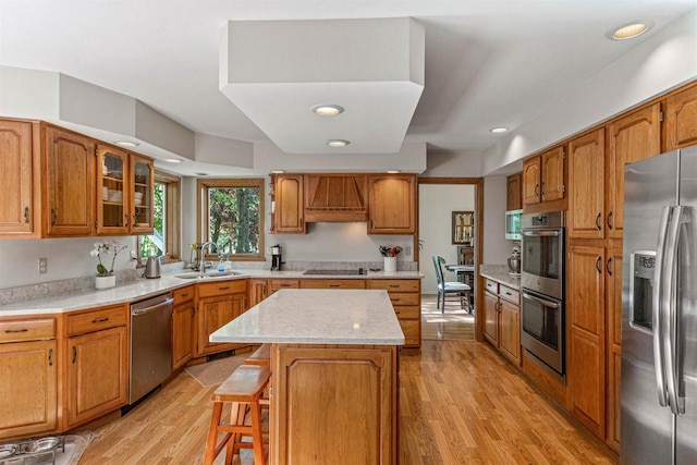 N1124 County Rd E, Waupaca, WI 54981 - kitchen with stainless steel appliances, a sink, a kitchen island, light wood-style floors, and brown cabinets