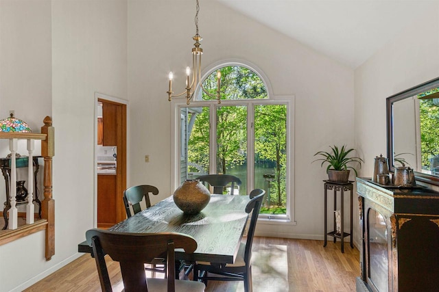 N1124 County Rd E, Waupaca, WI 54981 - dining area featuring light wood-type flooring, baseboards, high vaulted ceiling, and a chandelier