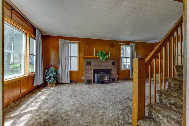 3218 Aalseth Ln, Stoughton, WI 53589 - unfurnished living room with carpet floors, a wood stove, wood walls, healthy amount of natural light, and stairway