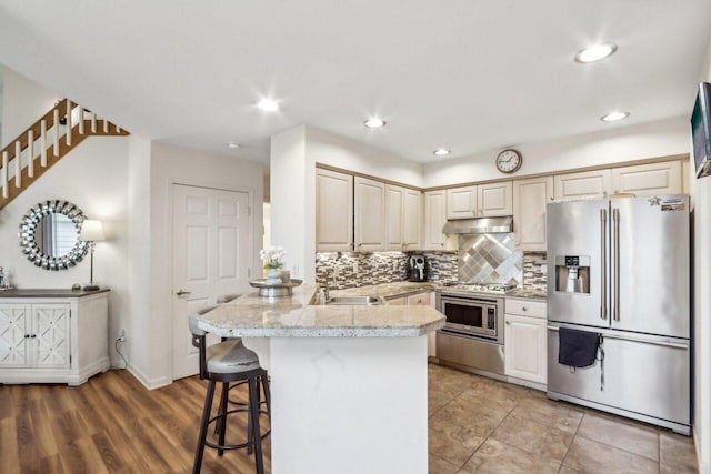 14048 W Waters Edge Trl, New Berlin, WI 53151 - kitchen with appliances with stainless steel finishes, a peninsula, backsplash, a sink, and a kitchen bar