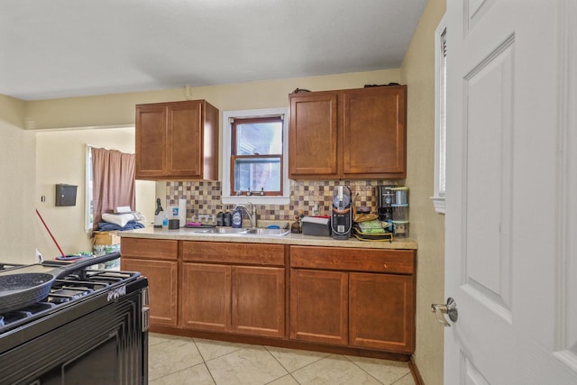 5936 N 35th St, Milwaukee, WI 53209 - kitchen featuring black gas range, light countertops, backsplash, a sink, and light tile patterned floors
