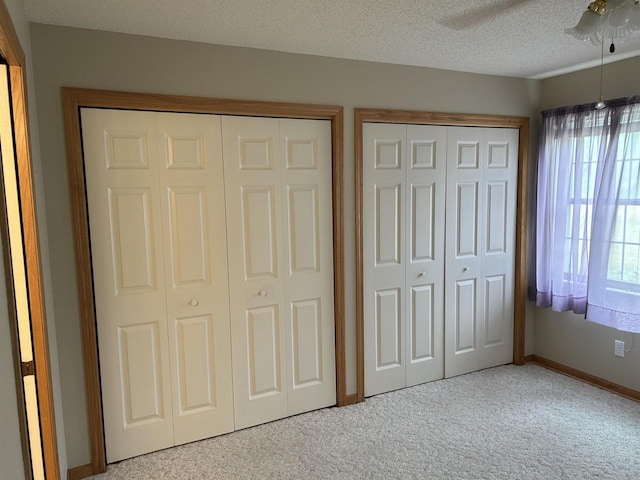 433 Eberlein Ct, Mauston, WI 53948 - unfurnished bedroom featuring multiple closets, carpet floors, baseboards, a ceiling fan, and a textured ceiling