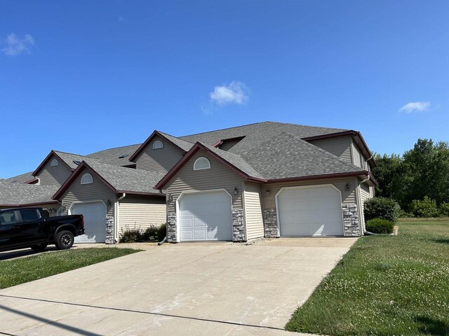 433 Eberlein Ct, Mauston, WI 53948 - view of front of house with a garage, a shingled roof, concrete driveway, and stone siding