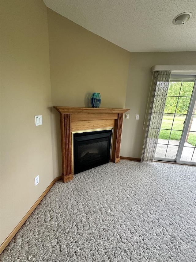 433 Eberlein Ct, Mauston, WI 53948 - unfurnished living room with carpet flooring, a glass covered fireplace, a textured ceiling, and baseboards