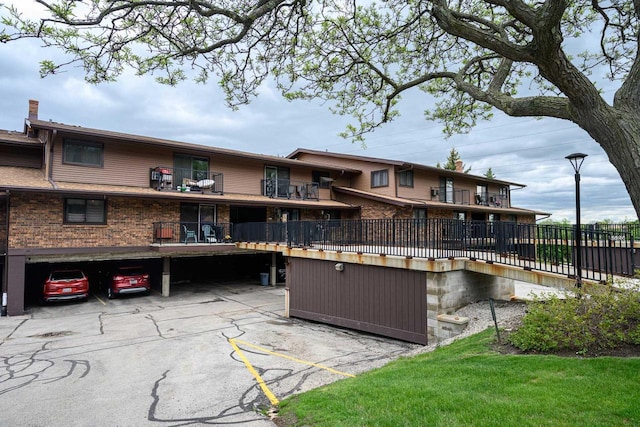 8525 W Waterford Ave Unit 1, Greenfield, WI 53228 - back of house with covered and uncovered parking, a balcony, and brick siding