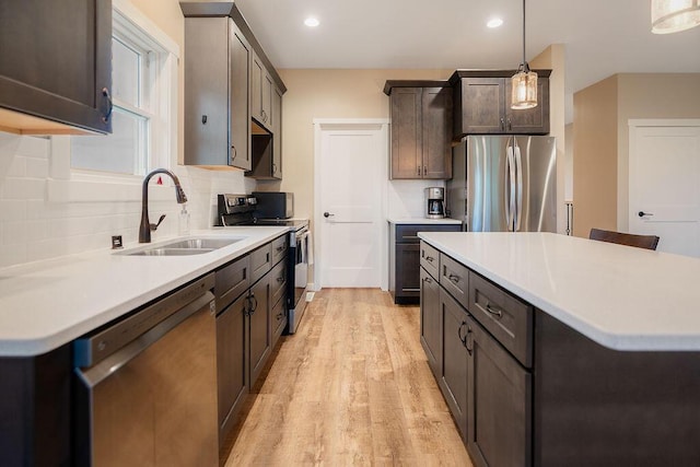 W4936 Battlestone Station Rd, La Crosse, WI 54601 - kitchen with stainless steel appliances, a sink, light wood-style flooring, tasteful backsplash, and light countertops