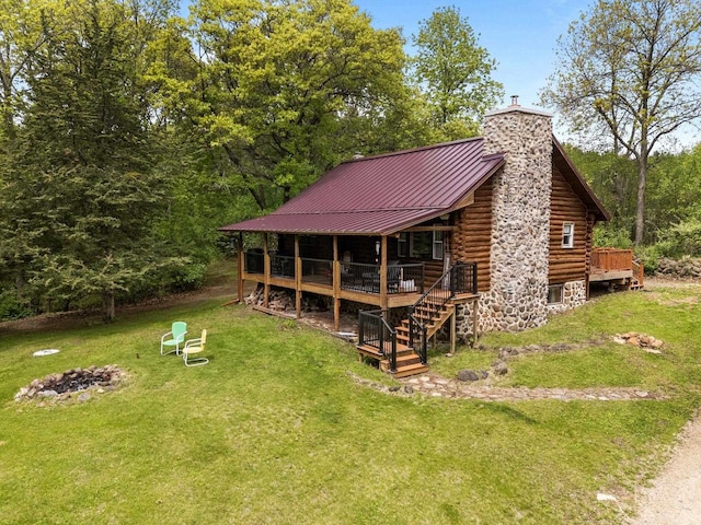W3276 Princeton Rd, Green Lake, WI 54941 - view of front facade with log siding, a chimney, a front lawn, an outdoor fire pit, and a wooden deck