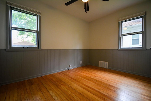 4407 N 57th St, Milwaukee, WI 53218 - spare room featuring wainscoting, light wood finished floors, a ceiling fan, and plenty of natural light