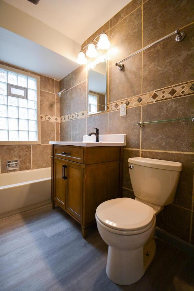 4407 N 57th St, Milwaukee, WI 53218 - bathroom featuring tile walls, toilet, vanity, wood finished floors, and  shower combination
