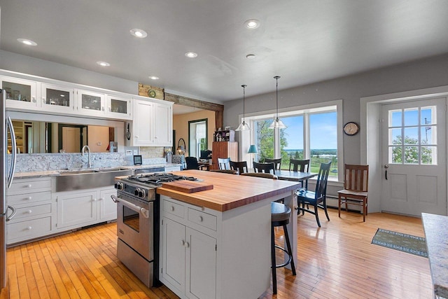 4105 Lime Kiln Rd, Green Bay, WI 54311 - kitchen with stainless steel appliances, a sink, butcher block counters, a kitchen bar, and white cabinetry