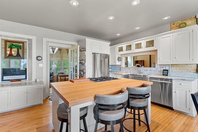 4105 Lime Kiln Rd, Green Bay, WI 54311 - kitchen with stainless steel appliances, a sink, light wood-type flooring, a kitchen island, and white cabinetry
