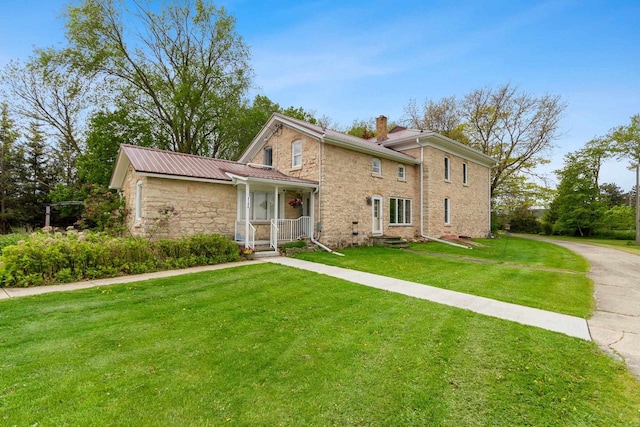 4105 Lime Kiln Rd, Green Bay, WI 54311 - traditional home featuring stone siding, a chimney, a front lawn, and metal roof