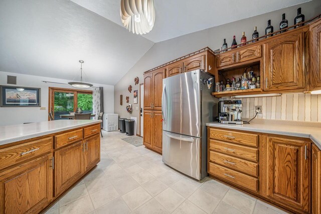 223 Willow Creek Rd, Rosendale, WI 54974 - kitchen with freestanding refrigerator, brown cabinetry, lofted ceiling, light countertops, and decorative light fixtures