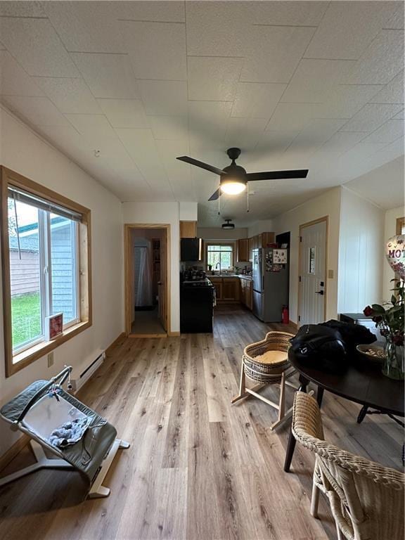 1010 Fillmore St, Black River Falls, WI 54615 - living area featuring light wood-style flooring, baseboard heating, and a ceiling fan