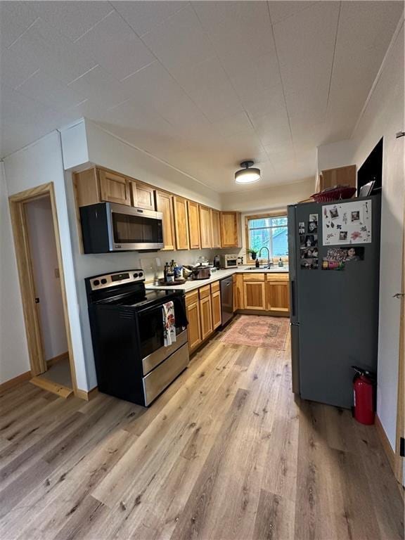 1010 Fillmore St, Black River Falls, WI 54615 - kitchen with appliances with stainless steel finishes, light wood-type flooring, light countertops, a sink, and baseboards
