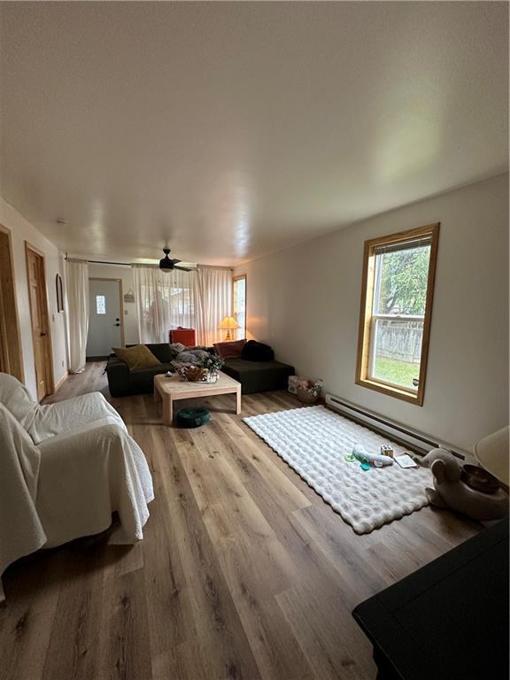 1010 Fillmore St, Black River Falls, WI 54615 - living area with healthy amount of natural light, wood finished floors, a baseboard radiator, and ceiling fan