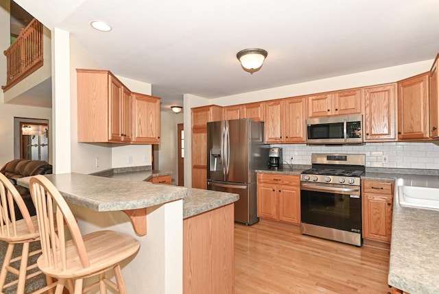 9165 S 47th St, Franklin, WI 53132 - kitchen with stainless steel appliances, tasteful backsplash, light wood-type flooring, a peninsula, and recessed lighting