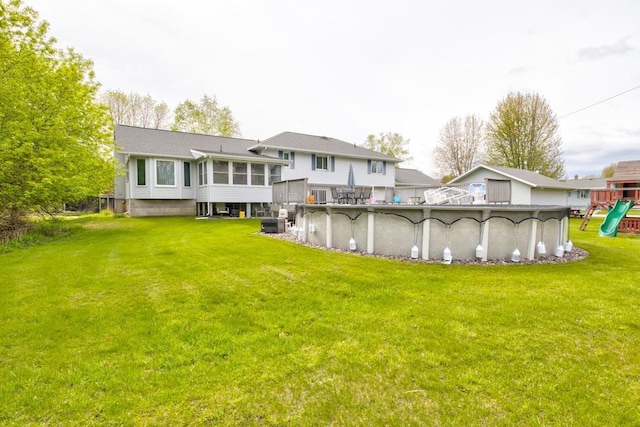 4100 15th St, Menominee, MI 49858 - rear view of house featuring a sunroom, a playground, a covered pool, a yard, and central AC unit