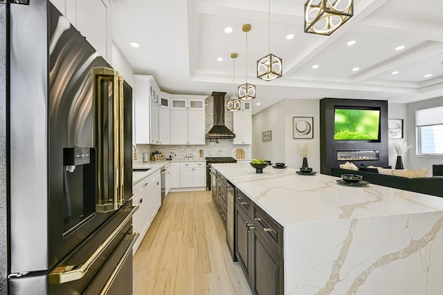 10500 W Vera Ave, Milwaukee, WI 53224 - kitchen with stainless steel appliances, wall chimney exhaust hood, a spacious island, light wood finished floors, and tasteful backsplash