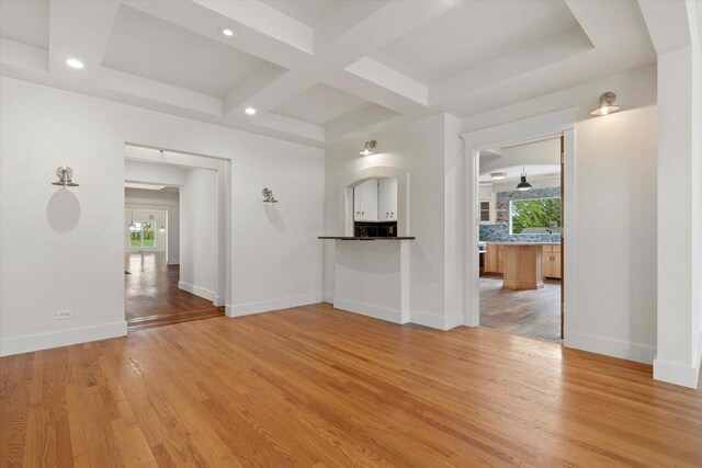6600 N Ballard Rd, Appleton, WI 54913 - unfurnished living room with healthy amount of natural light, light wood-type flooring, coffered ceiling, baseboards, and beam ceiling
