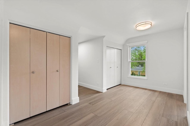 6600 N Ballard Rd, Appleton, WI 54913 - unfurnished bedroom featuring baseboards, light wood finished floors, and multiple closets