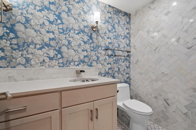 6600 N Ballard Rd, Appleton, WI 54913 - bathroom featuring wallpapered walls, toilet, vanity, and tile walls
