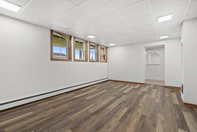 6600 N Ballard Rd, Appleton, WI 54913 - below grade area featuring a baseboard radiator, a drop ceiling, wood finished floors, and baseboards