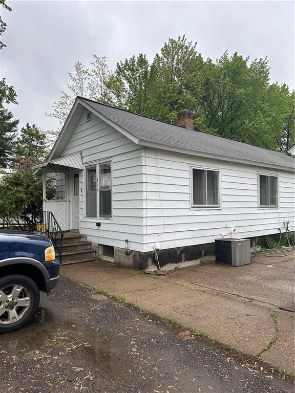 315 Armstrong Ave, Black River Falls, WI 54615 - view of front facade with a chimney, central air condition unit, and roof with shingles