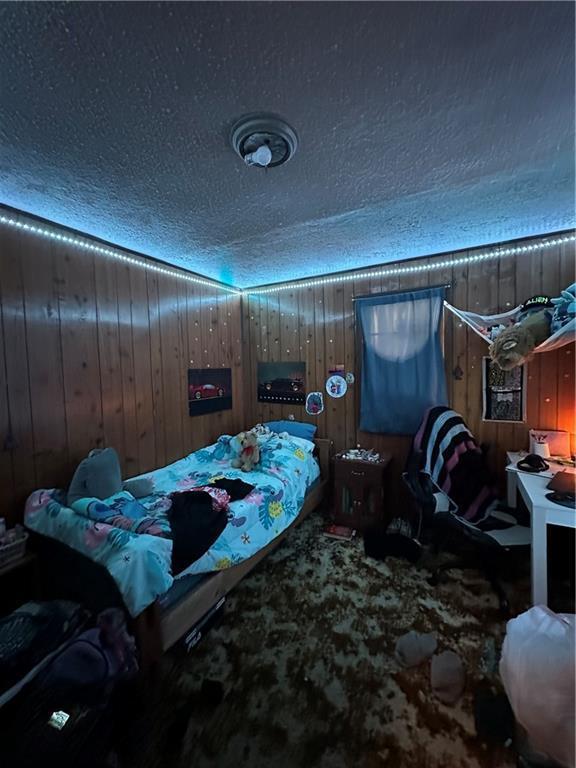 315 Armstrong Ave, Black River Falls, WI 54615 - bedroom featuring a textured ceiling, wood walls, and carpet floors