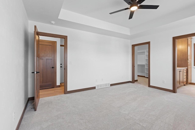 513 Kirkland Ave, Algoma, WI 54201 - unfurnished bedroom featuring light carpet, baseboards, a walk in closet, a raised ceiling, and ensuite bathroom