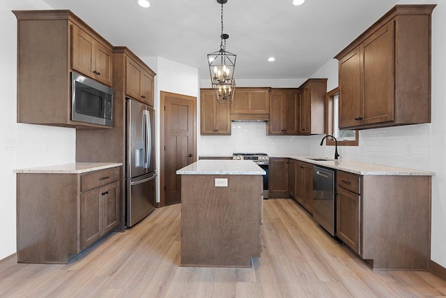 513 Kirkland Ave, Algoma, WI 54201 - kitchen with appliances with stainless steel finishes, a sink, light wood-style floors, a center island, and tasteful backsplash