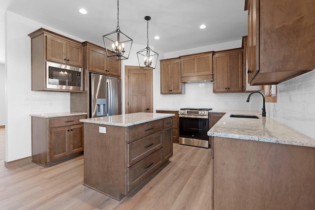 513 Kirkland Ave, Algoma, WI 54201 - kitchen featuring appliances with stainless steel finishes, a sink, light wood-style flooring, a center island, and light stone countertops