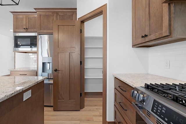 513 Kirkland Ave, Algoma, WI 54201 - kitchen featuring stainless steel appliances, light wood-style floors, decorative backsplash, and light stone counters
