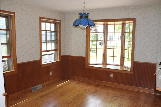 620 Oak St, Winneconne, WI 54986 - unfurnished dining area with wainscoting, hardwood / wood-style flooring, plenty of natural light, wood walls, and wallpapered walls