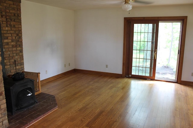 620 Oak St, Winneconne, WI 54986 - unfurnished living room with a wood stove, baseboards, ceiling fan, and wood finished floors