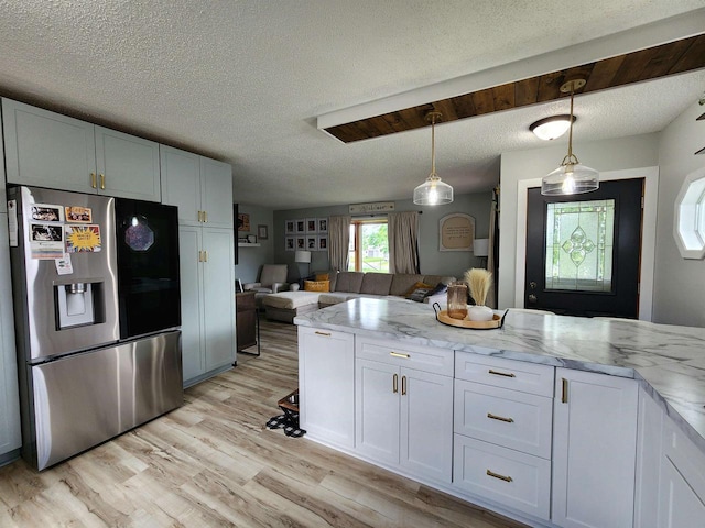 307 W Jackson St, Tomah, WI 54660 - kitchen with stainless steel fridge with ice dispenser, open floor plan, light stone counters, light wood-type flooring, and a textured ceiling