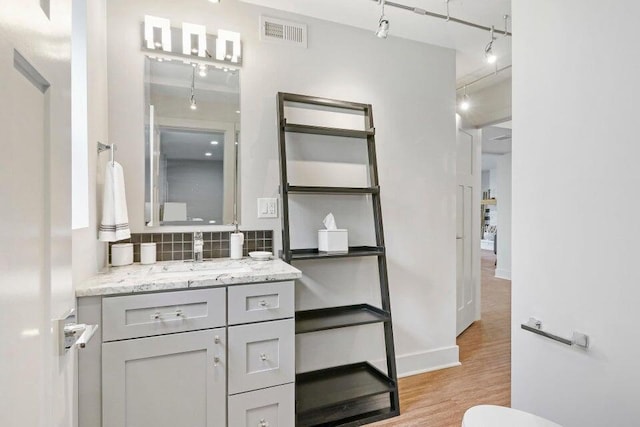 24722 84th St, Salem, WI 53168 - bathroom featuring tasteful backsplash, wood finished floors, rail lighting, vanity, and toilet