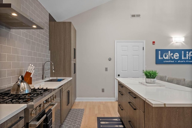 W3920 Lake Shore Dr, Lake Geneva, WI 53147 - kitchen with wall chimney exhaust hood, stainless steel range, a sink, light wood-style flooring, and light countertops