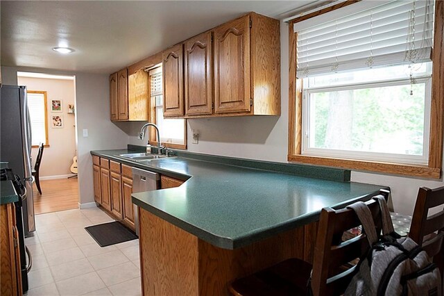 203 E Maple St, Thorp, WI 54771 - kitchen featuring dark countertops, a peninsula, a kitchen breakfast bar, and brown cabinets