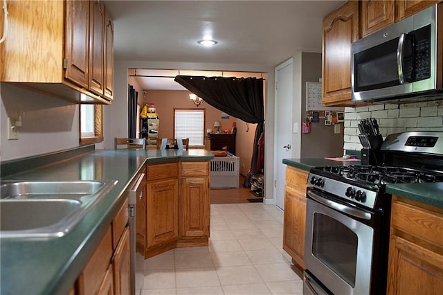 203 E Maple St, Thorp, WI 54771 - kitchen featuring stainless steel appliances, decorative backsplash, brown cabinetry, and dark countertops
