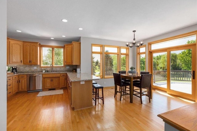 15210 Painters Lane Cir, Stillwater, MN 55082 - kitchen featuring dishwasher, a peninsula, a breakfast bar area, a chandelier, and light wood-type flooring
