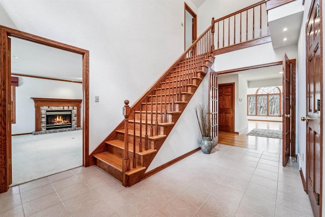 79 Oakridge Ct, Fond Du Lac, WI 54937 - stairway with a brick fireplace, tile patterned flooring, carpet flooring, baseboards, and a towering ceiling