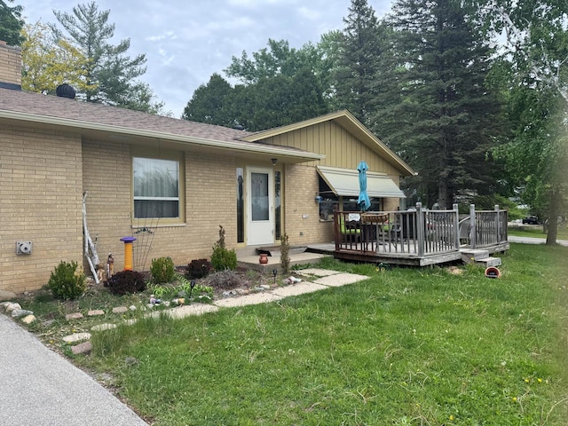 1306 Grandview Ave, Oconomowoc, WI 53066 - view of home's exterior with a yard, brick siding, a wooden deck, and a chimney